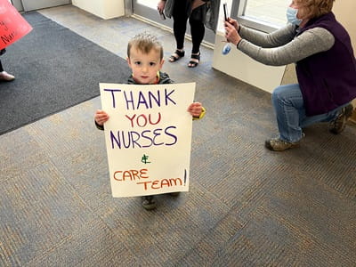 child holds a sign thanking nurses